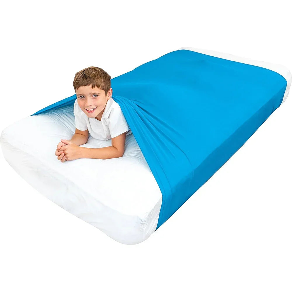 Child using a blue sensory compression sheet on a bed for calming and focus support