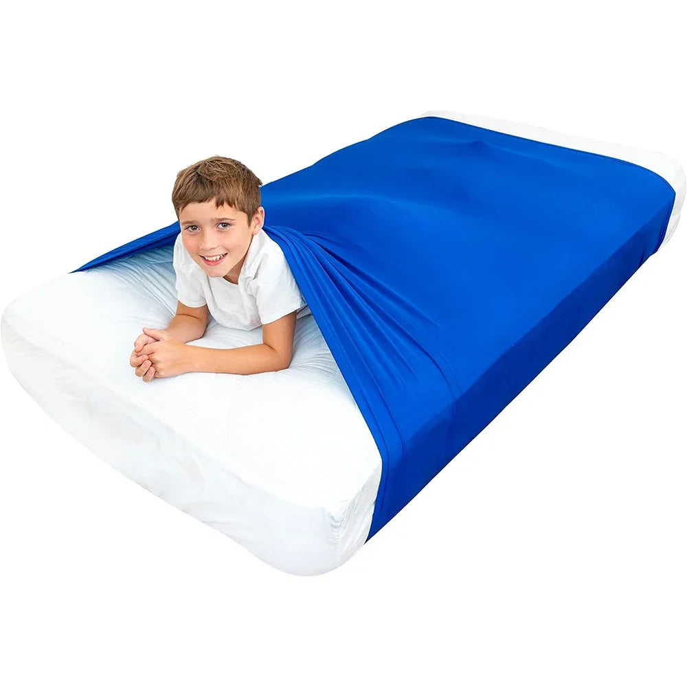 Child in blue sensory compression sheet on bed for calming and focus support