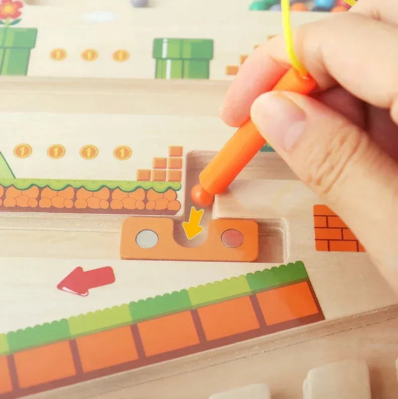 Hand using orange magnetic pen on colorful wooden sensory maze board for kids